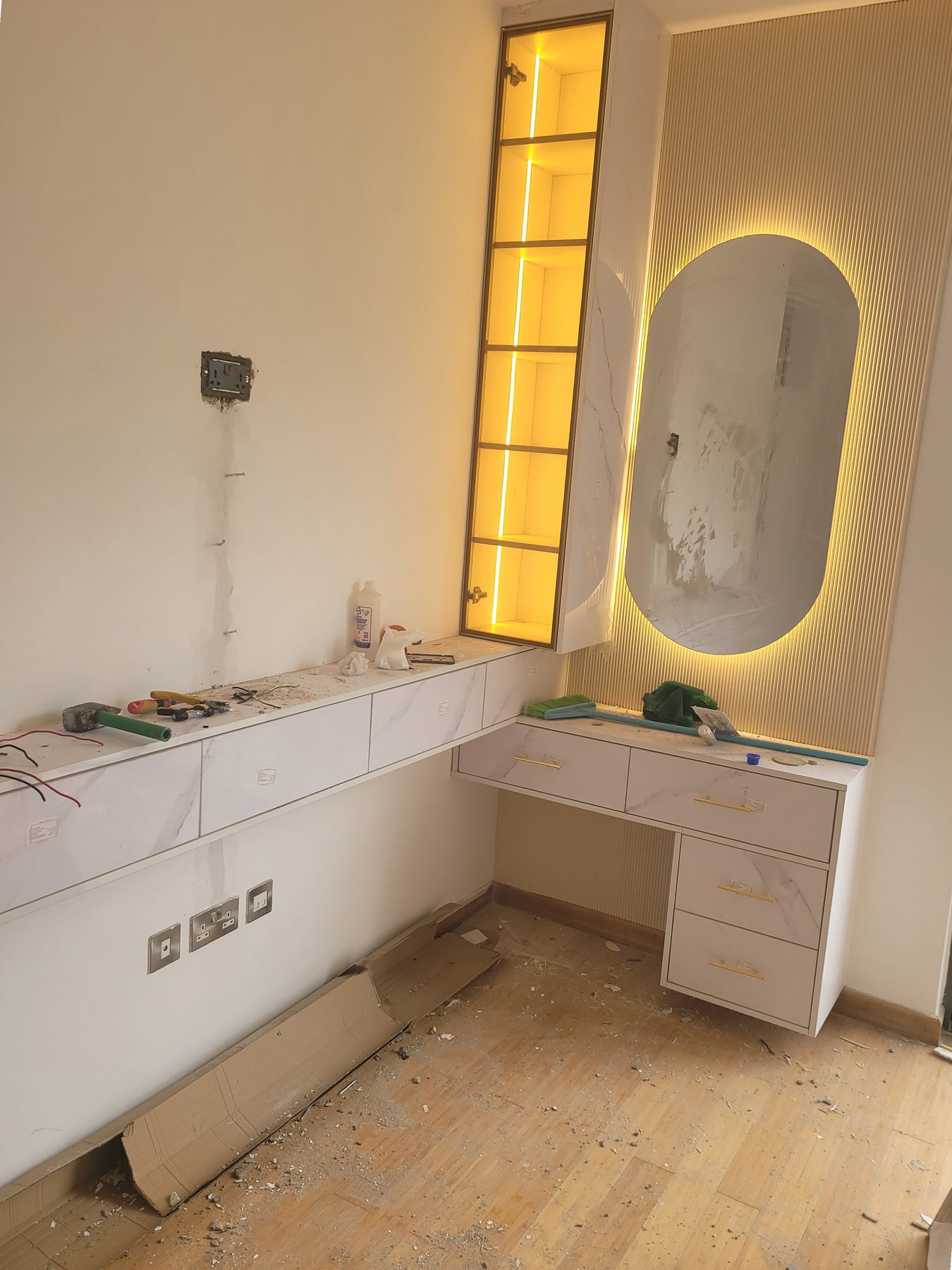 Dressing table with a backlit oval mirror on a fluted gold panel