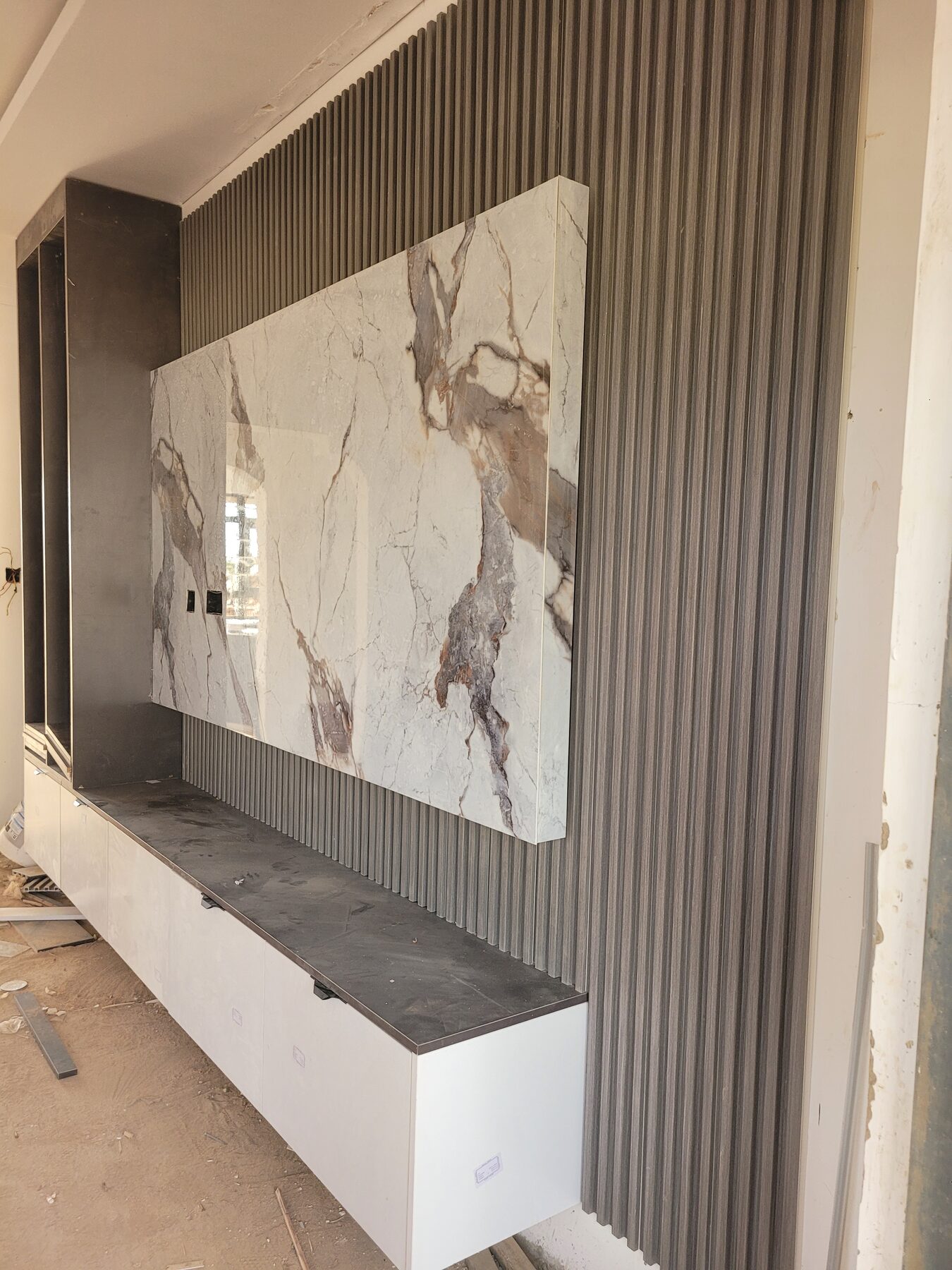 Fluted gypsum panelling with a book-matched marble television feature wall, installed by Full Interior Designs Kenya