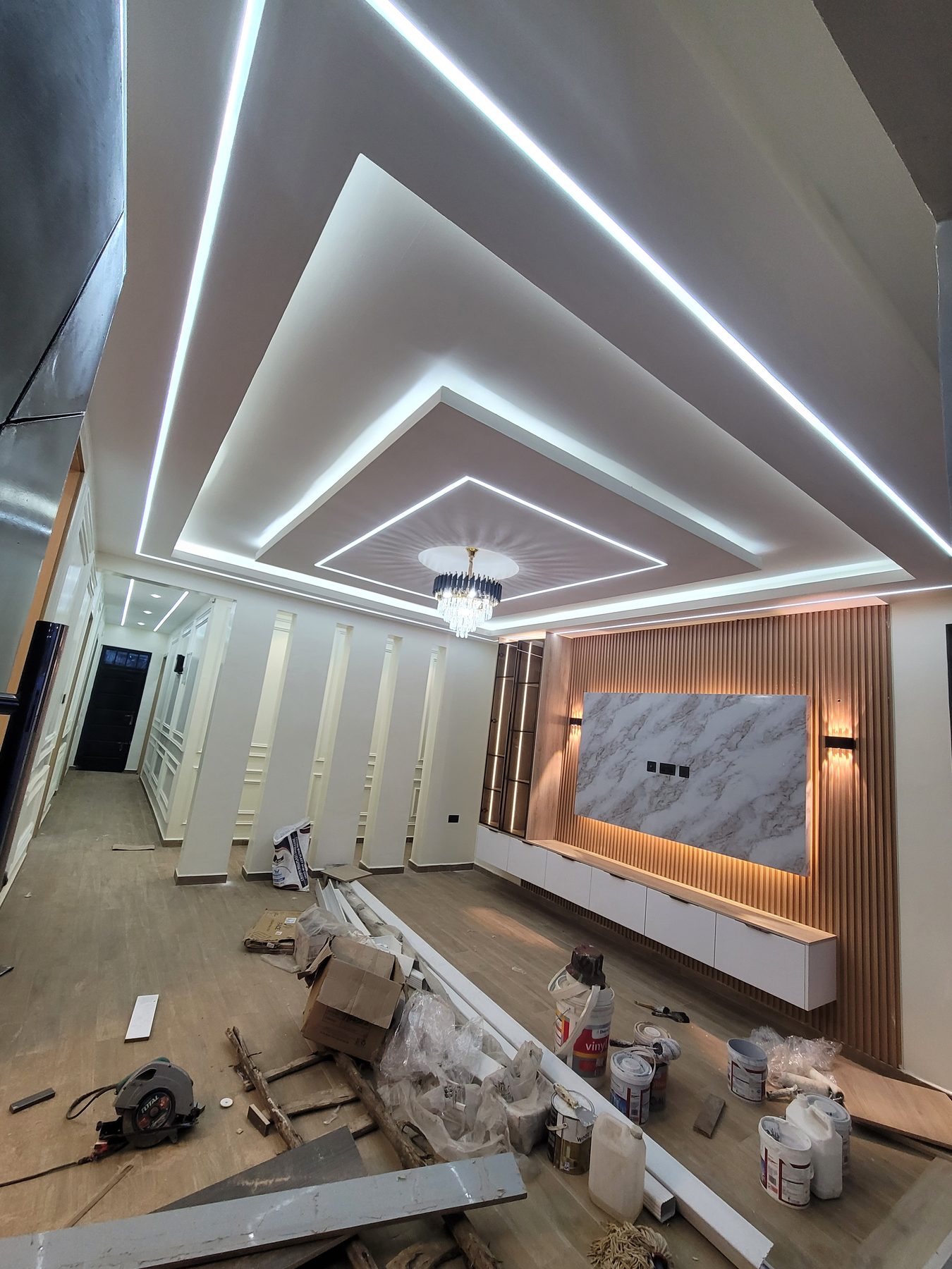 Pitched gypsum ceiling with LED coves above a marble TV wall