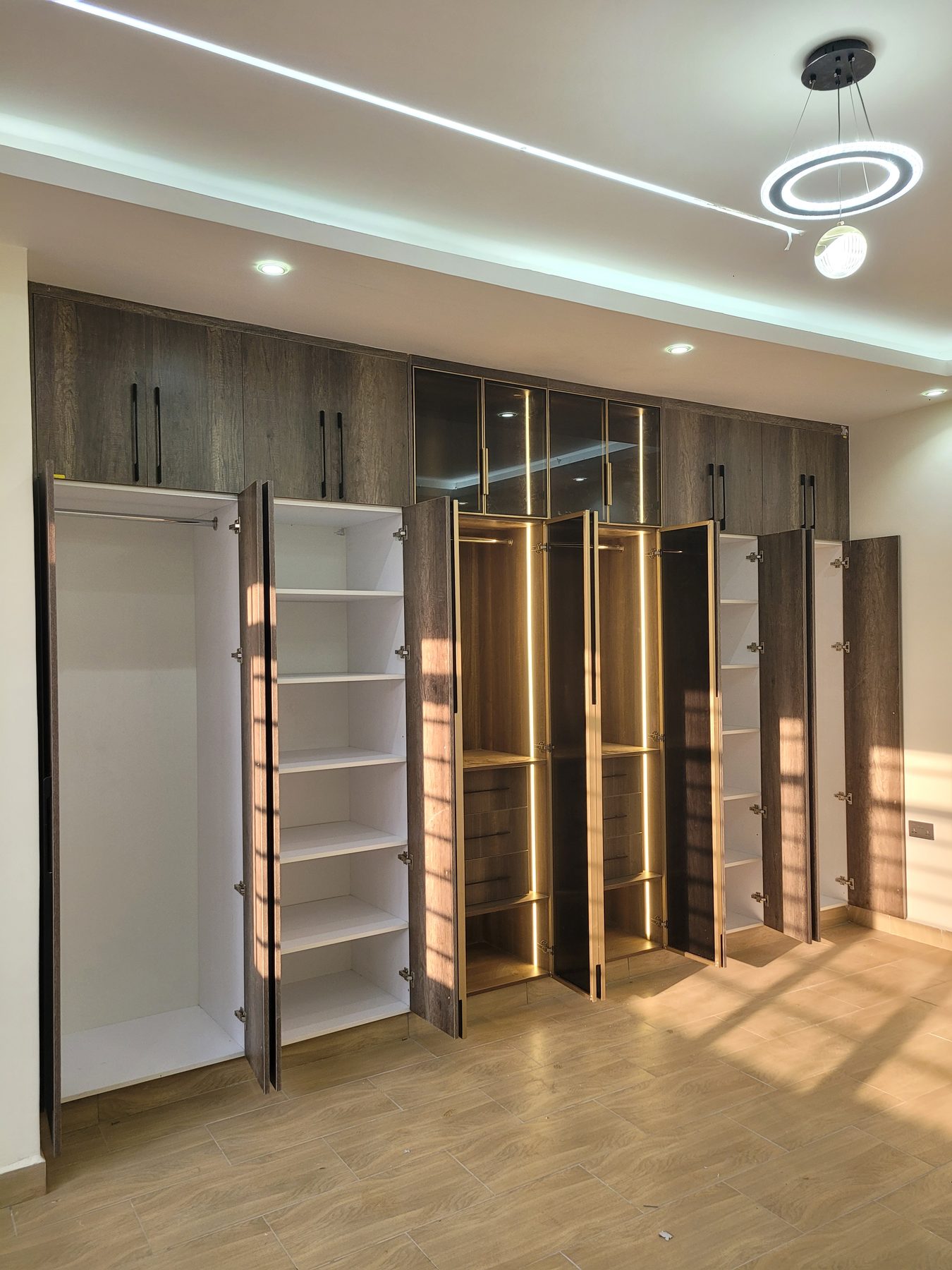 Walk-in wardrobe with open doors and warm LED-lit hanging space